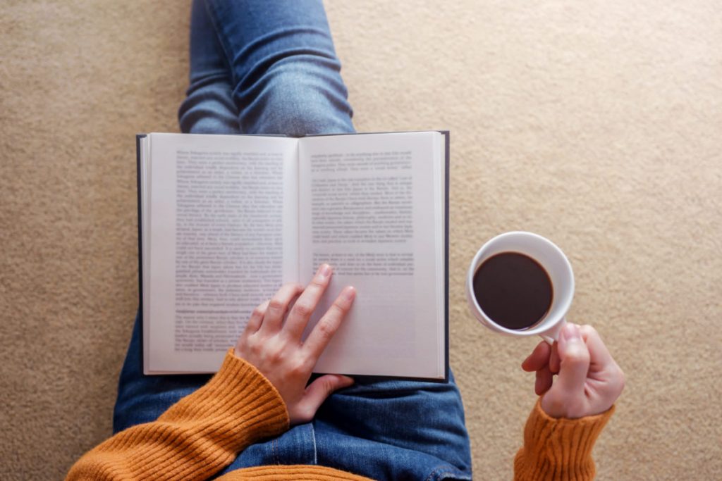 Person reading a book with a cup of coffee